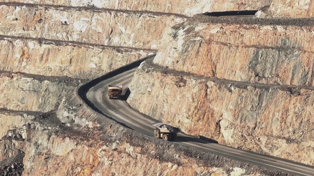 Western Australia / Australia - Circa 2000s: Large mining truck hauls rock and ore from depths of huge open cast mine pit. Mineral and metal mining concept. Late afternoon light. HOT AIR DISTORTION.