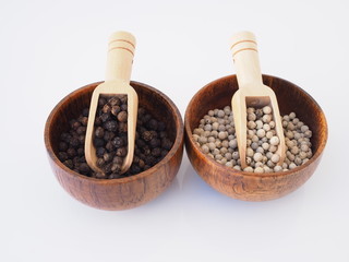 dried food with white pepper and black pepper in wooden bowl isolated on white background.