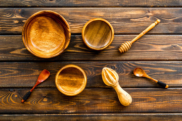 Set of rustic wooden tableware - bowls and utensils on dark wooden background top view pattern