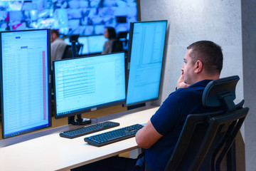 Side view of security system operator using walkie-talkie while looking at CCTV footage