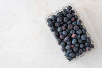 Open clamshell container of blueberries on a white granite counter