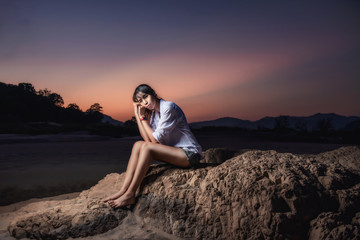 Woman traveler sitting on a rock in sea shore of the Thailand beach