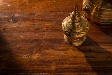 Fototapeta na wymiar Close up of traditional brass lamp artifacts from southern India on a wooden table