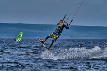 A male kiter slides on the surface of the water. Splashes of water fly apart.