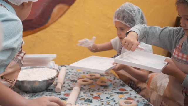 Young girls taking flour for preparation pastry on baking class in culinary school. School girl cooking donut on cooking master class on school lesson