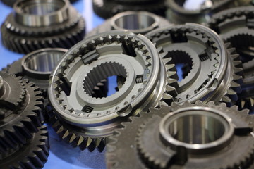 More car gearbox pinion cog wheels and synchronisers on blue background close up, vehicle gears...