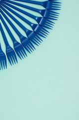 Blue plastic forks on a blue background, vertical orientation, copy space