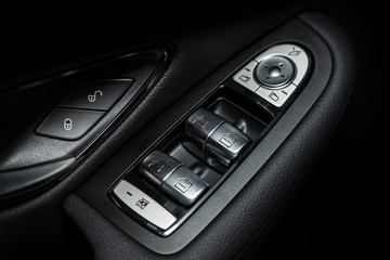 Close up of a door control panel in a new modern car. Arm rest with window control panel, door lock button, and mirror control..