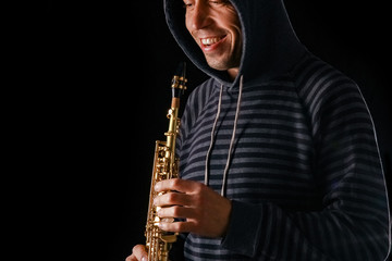 Naklejka premium soprano saxophone in the hands of a guy on a black background