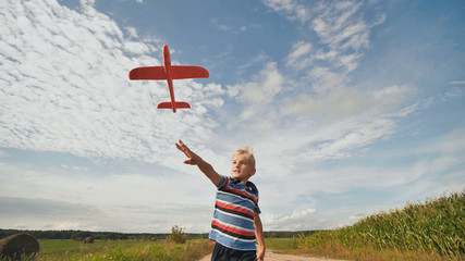 A little boy runs and launches a paralon toy airplane.