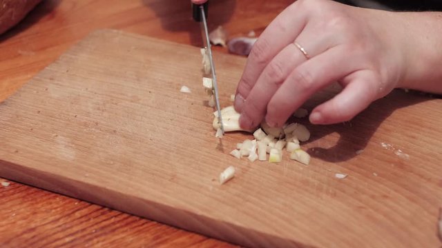 Woman's hands chop the last clove of garlic. Preparations for making a sandwich with garlic. Close up.