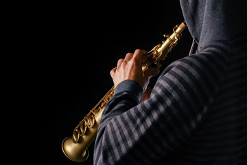 soprano saxophone in the hands of a guy on a black background