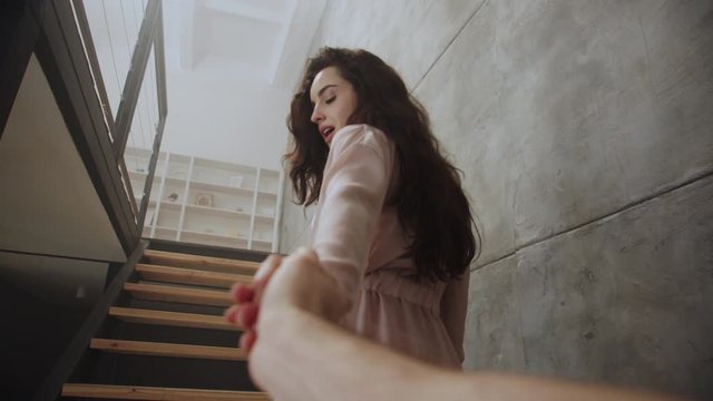 Sexy woman holding man hand at home. Cute girl tempting boyfriend.