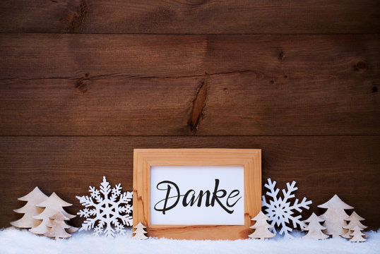 German Calligraphy Danke Means Thank You. White Christmas Ornament Like Snowflake And Tree. Wooden Background With Snow