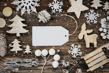 One White Label With Copy Space. Frame Of Christmas Decoration Like Sled, Tree, Star And Fir Cone. Wooden Background With Snowflakes