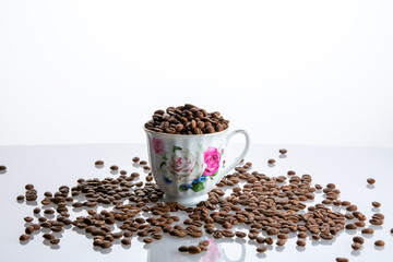 Cup full of coffee seeds white background