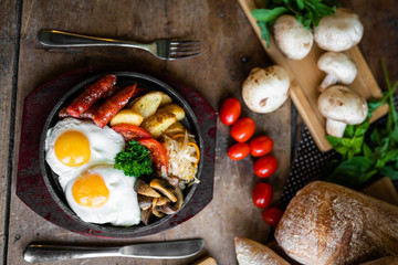 breakfast fried scrambled eggs with sausages and potatoes in a pan on a beautiful background