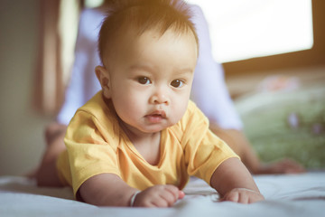 Adorable asian baby crawling at bedroom after wake up in the morning,Mother take care and support,Childhood and baby care concept,Selective focus