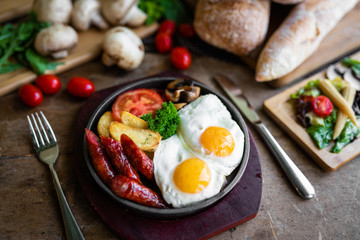 breakfast fried scrambled eggs with sausages and potatoes in a pan on a beautiful background