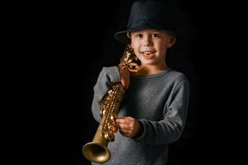 happy child plays saxophone in studio