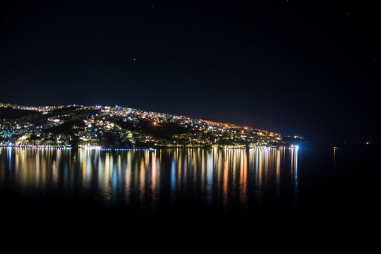 Sea bay at night. Reflection of light of lanterns on sea water. Beautiful night photo.