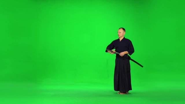 Masculine Kendo warrior practicing martial art with the bamboo bokken on green screen.