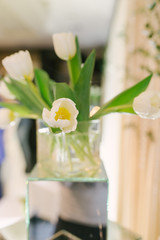 Bouquet of white tulips in a glass vase in the interior decor or wedding. Selective focus