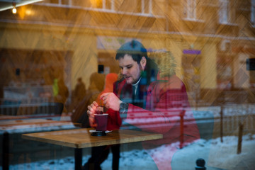 man in cafe in red winter coat drinking tea warming up