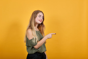 Attractive young woman in casual shirt showing on workspace, staying aside isolated on orange wall...
