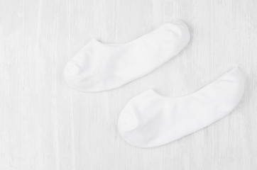 Pair blank white small, low socks flat lay on white wood board, side view - mock up for design, print, presentation, advertising, top view, copy space.
