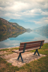 Naklejka na ściany i meble Wooden bench by the lake in focus. Lago di Cavedine. Italy. Arco