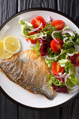 fried dorado fillet with fresh salad close-up on a plate. Vertical top view