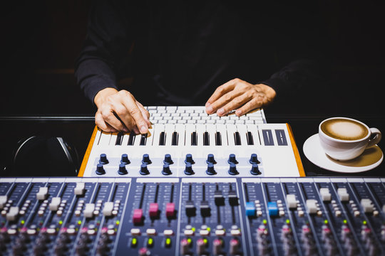 male musician hands playing midi keyboard for recording music on computer in home recording studio. music production concept