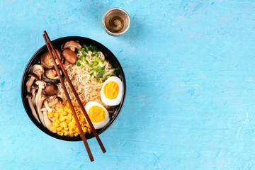 Ramen. Soba noodles with boiled eggs, shiitake mushrooms, and vegetables, top shot on a blue...