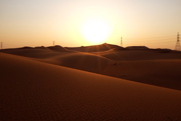 Fototapeta na wymiar Sunrise in a desert landscape with power transmission lines near Riyadh in Saudi Arabia. Energy Industry