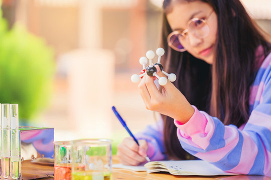 Asian teenage girl in elementary science class doing chemical model form and make a short note. Education concept. Selected focus