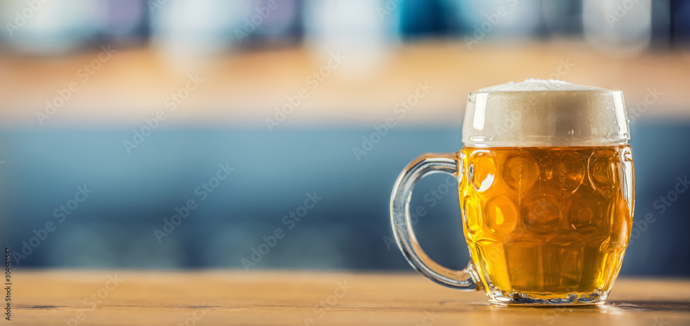 Wall mural Mug of cold beer on bar counter in pub or restaurant