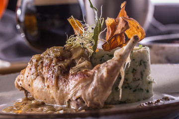 Rabbit leg with mashes potatoes and decoration on plate in restaurant