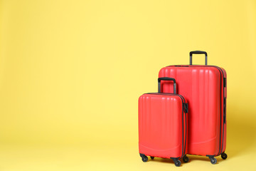Stylish red suitcases on yellow background. Space for text