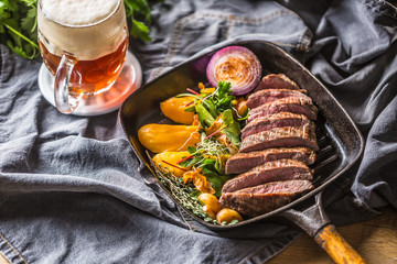 Beef flank steak in grill pan with batata puree garlic herb decoration and draft beer