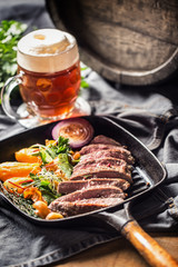 Beef flank steak in grill pan with batata puree garlic herb decoration and draft beer