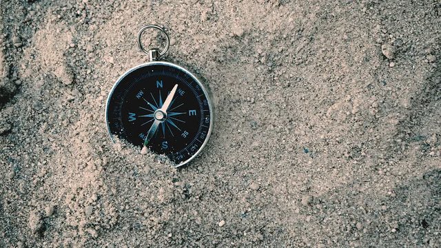 Close up compass in the sand , search direction for travel or journey , search business or life direction goal symbol concept