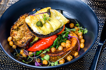A dish of vegetables, Halloumi, Pumpkin, Bell Pepper and Eggplant stacked up on a dark blue plate.