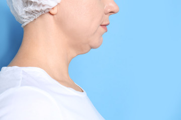 Mature woman with double chin on blue background, closeup. Space for text