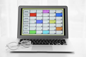 Modern laptop with calendar on screen in office