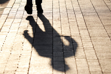 Silhouette and shadow of man walking the street, dramatic colors. Concept of criminal, murderer or...