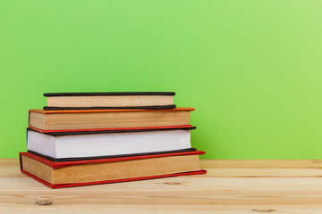 Simple composition of many hardback books, raw of books on wooden table and light green background