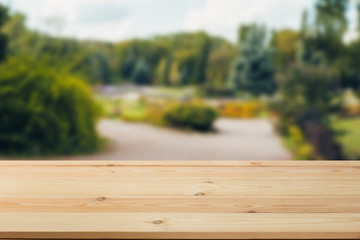 Wooden  table in front of a blurred background. Perspective brown wood with a blurry background of nature or park - can be used to showcase or assemble your products. Mock up to display the product.