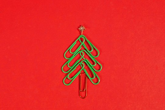 Concept merry xmas in the office. Xmas tree made of paper clips on the red background. paper clip Christmas tree. Christmas background.