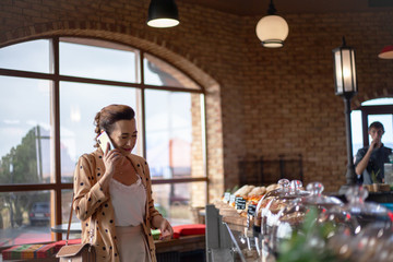 Matured middle aged woman dressed style fasnion clothes chooses the pastry bakery on showcase table in cafe.